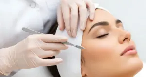 Woman receiving Dermaplaning Treatment in Orchard Park, NY, from a professional using a scalpel for smooth, glowing skin.